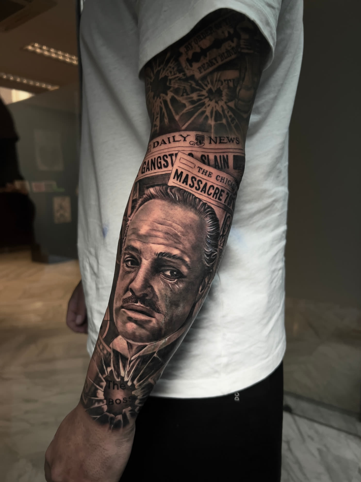 Manga realista de El Padrino con periódicos y lettering en el antebrazo, black and grey en Castellón